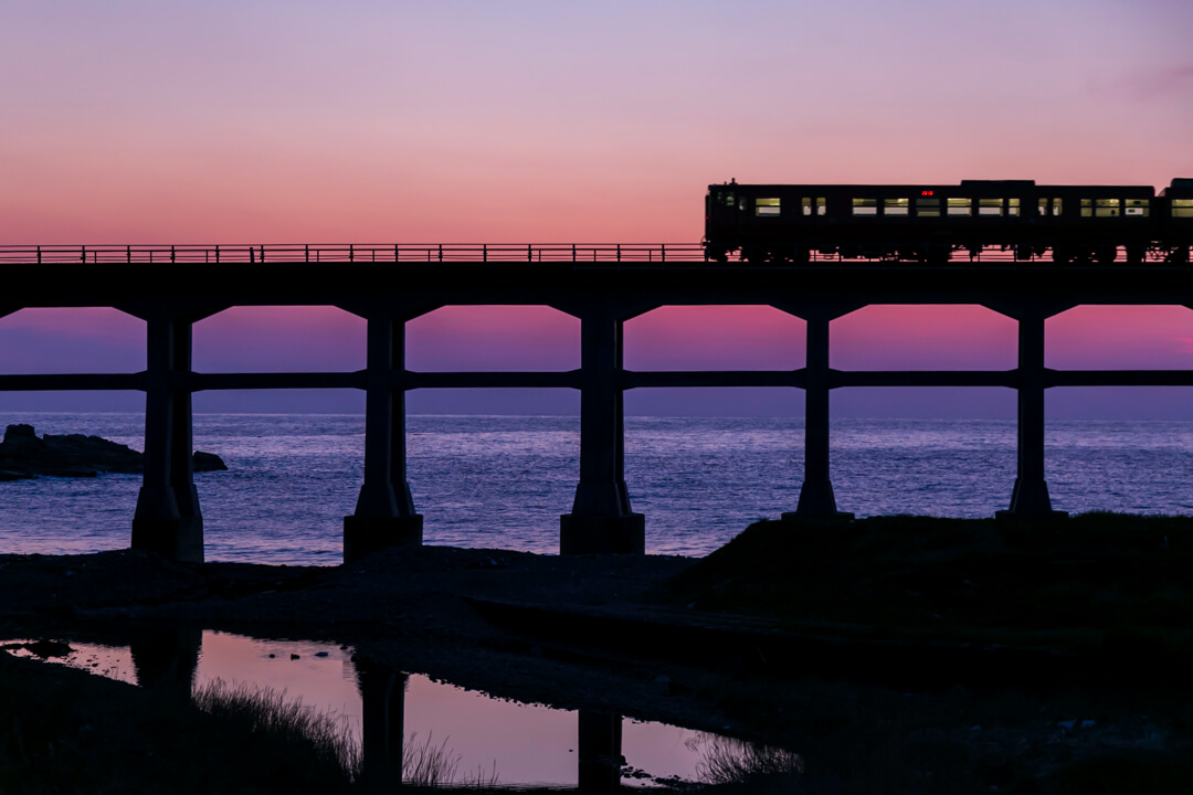 黄昏時に惣郷川橋梁の上を走る列車の写真