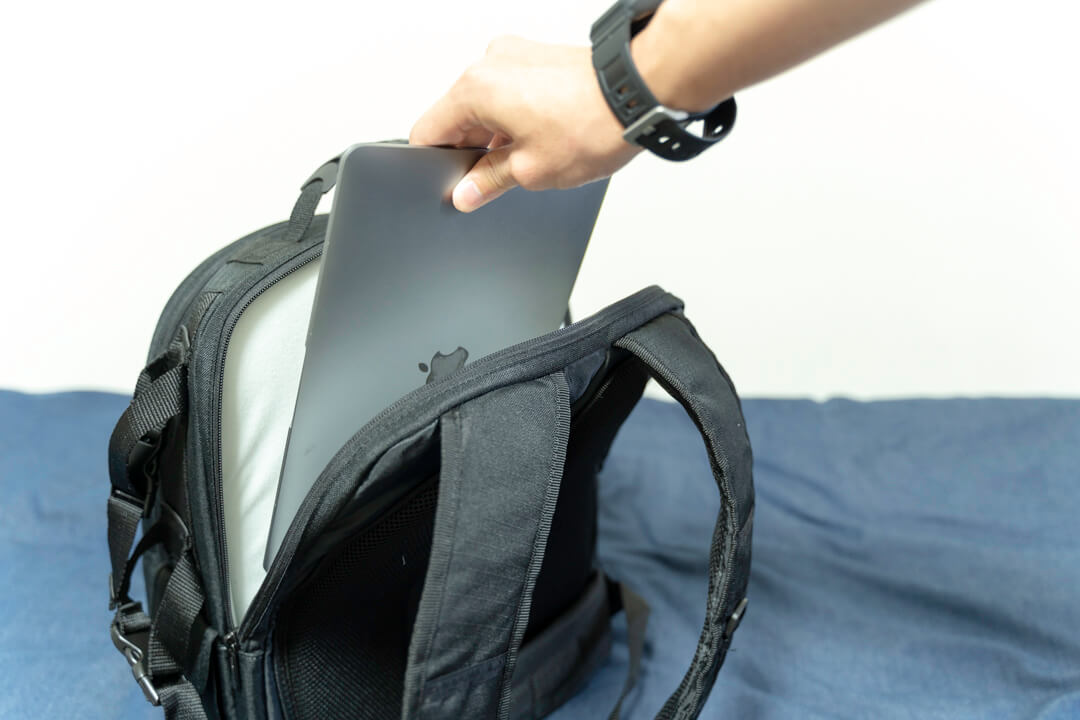 Amazonベーシックのカメラバッグ（22.8L）の背面ポケットにノートパソコンを収納する様子